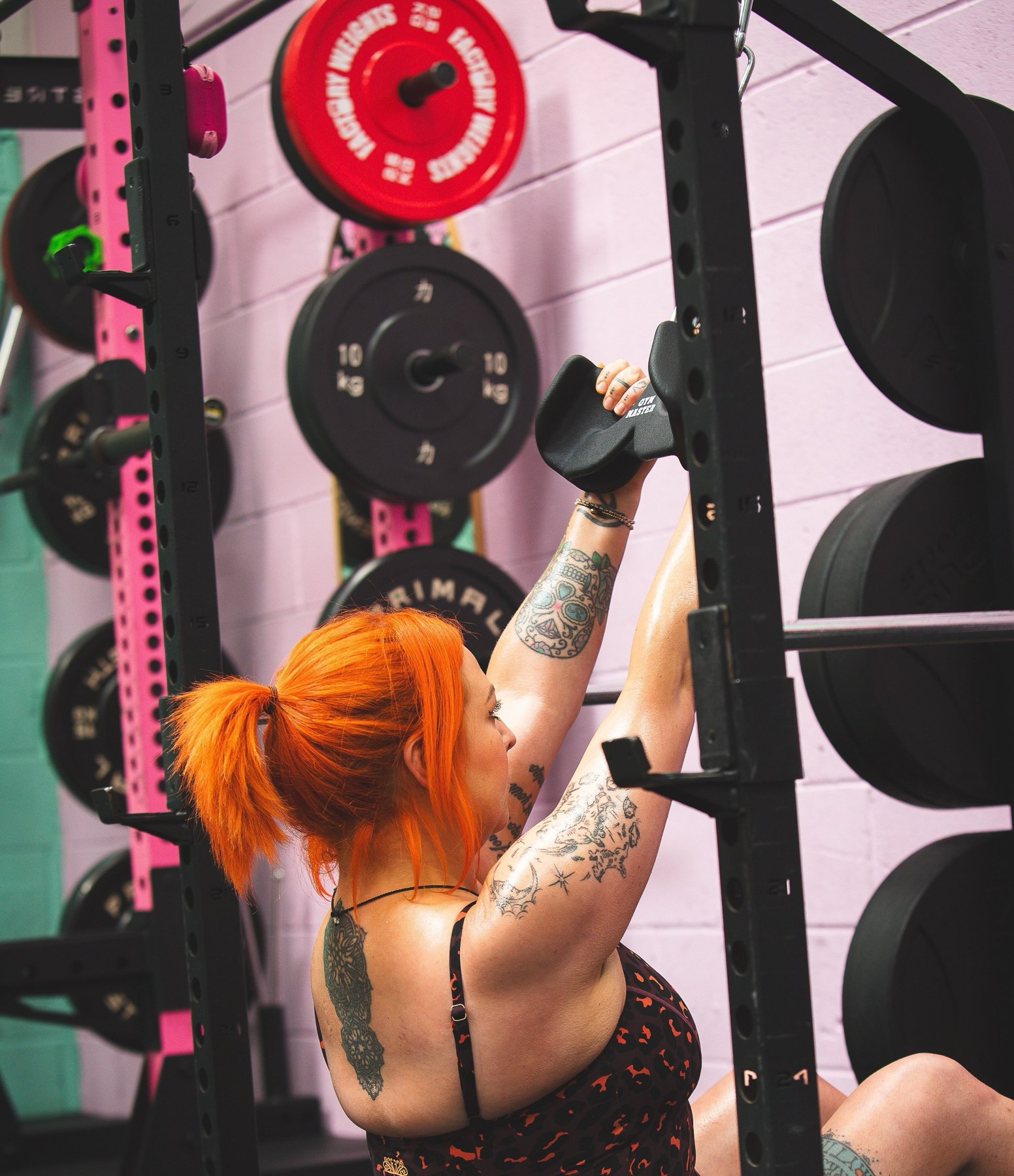 A member loading weight plates onto a hot-pink rack